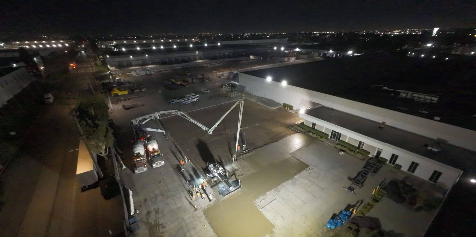 MGB project photo: aerial night view of a large concrete pour beside a warehouse, pump booms and trucks working under floodlights