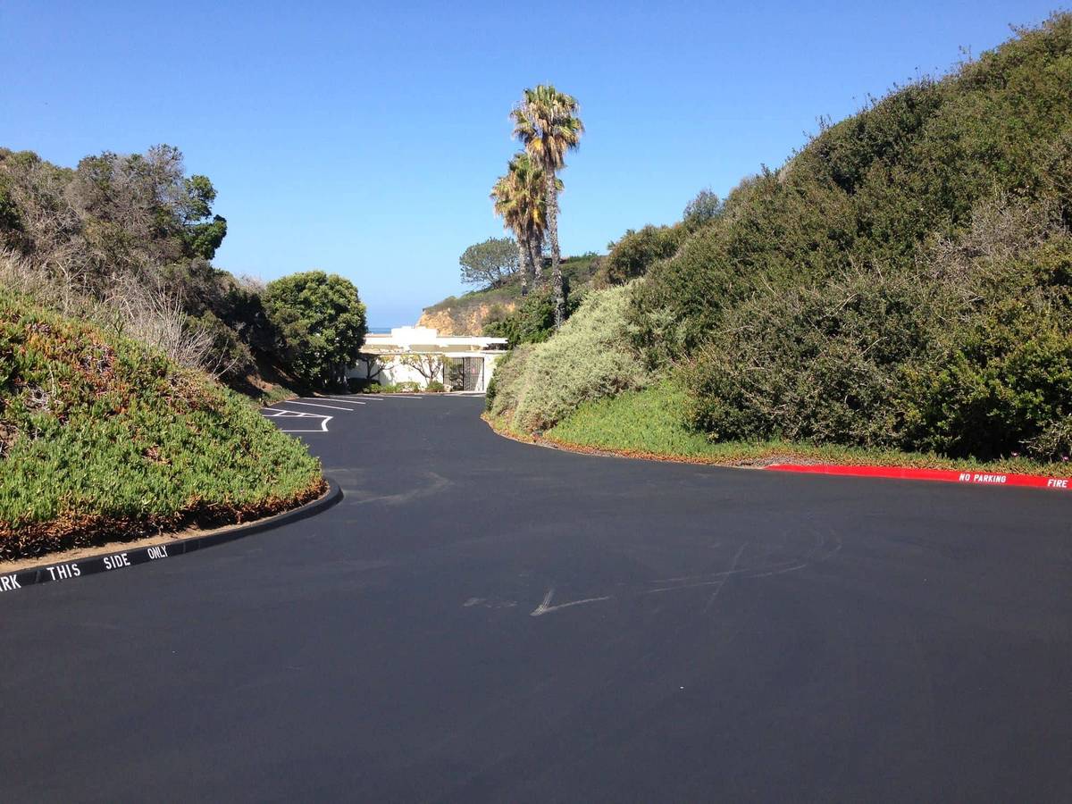 MGB project photo: hillside drive finished in uniform black sealcoat with freshly painted red curbs, Irvine Cove
